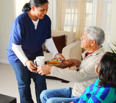 caregiver giving food to a senior man