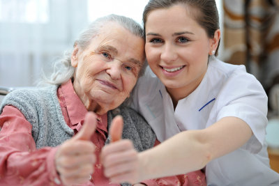 senior woman and a caregiver giving thumbs up